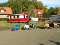 Triebwagen 187 001 bei der Fahrt durch Harzgerode mit diversen Straßenfahrzeugen im Vordergrund